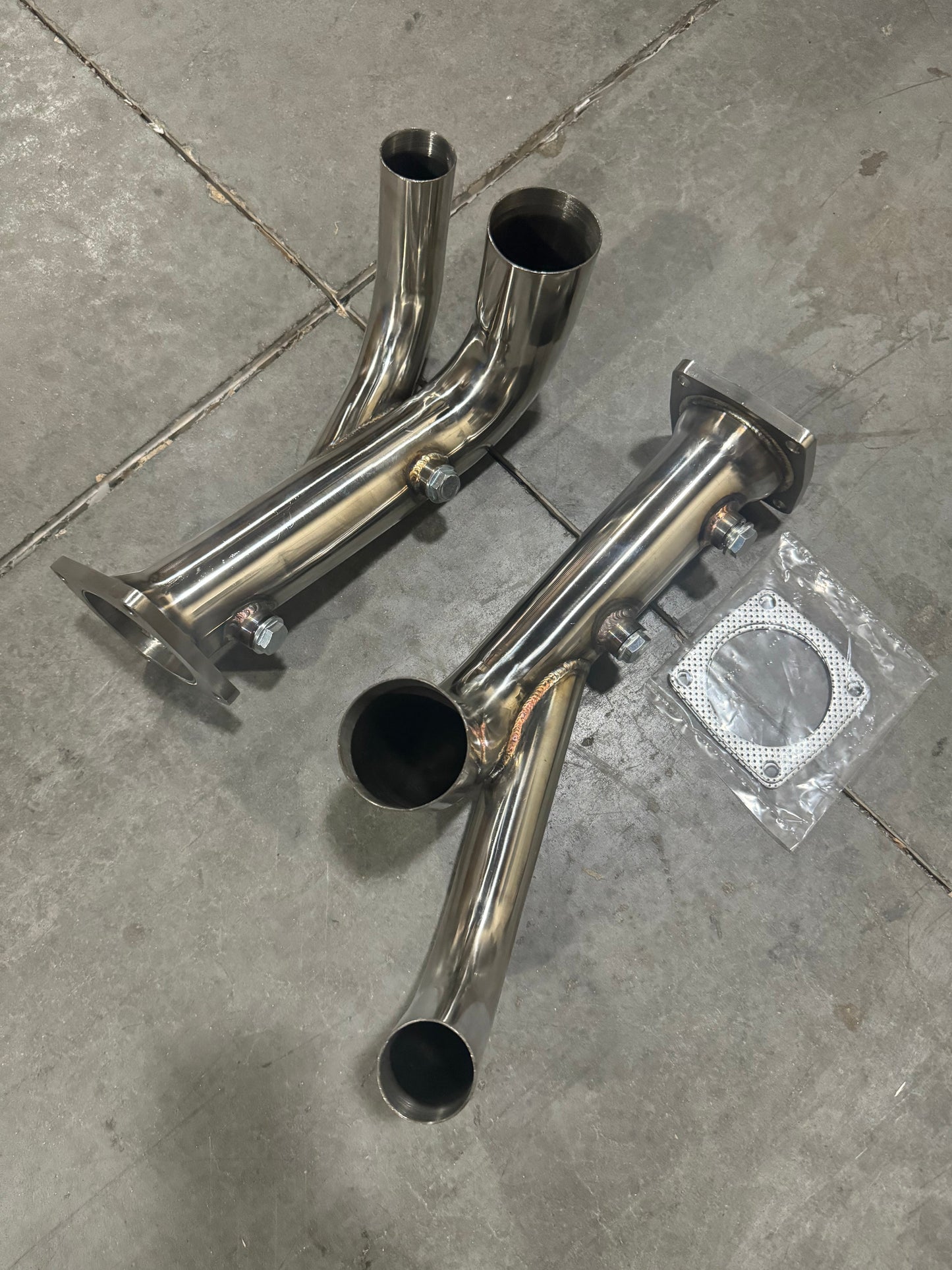 Porsche 991.2 Carrera exhaust parts with PSE Sport Exhaust Cat Bypass Pipes by JackSpania Racing, showing the metallic pipes and fittings.