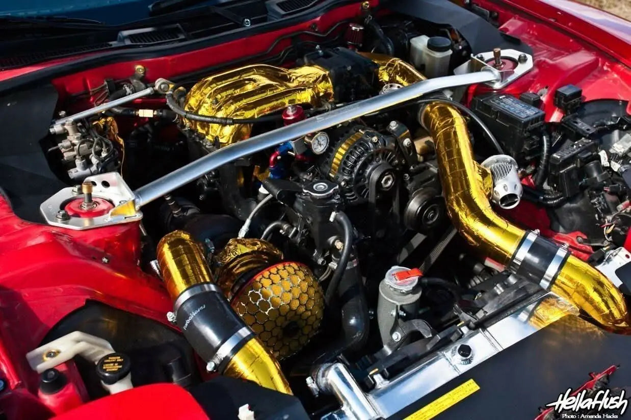 Giant gold reflective thermal heat shield tape roll for turbo engine protection by Jack Spania Racing, showing reflective surface and roll.