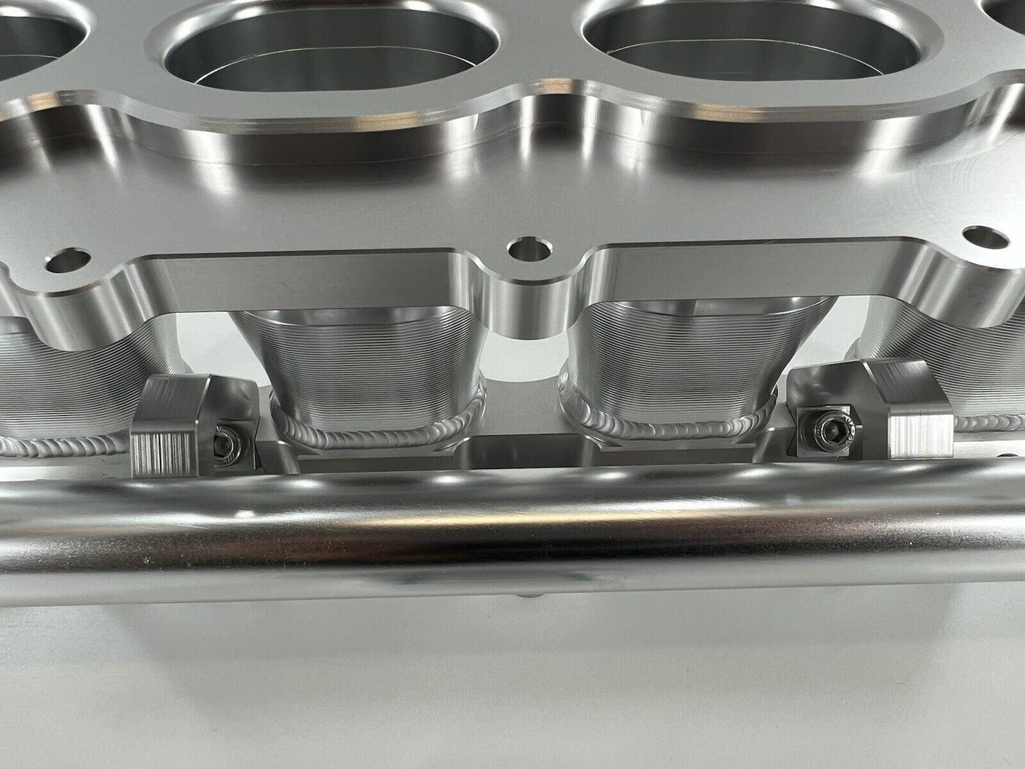 Jack Spania Racing billet K Series intake manifold adapter for Skunk2 Ultra engine parts, shown on a clean engine component.