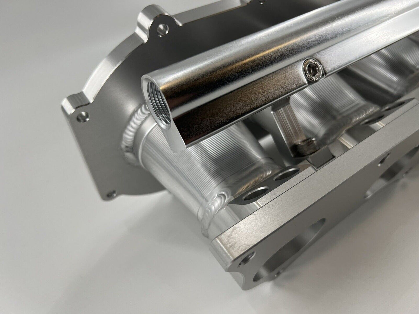 Jack Spania Racing billet K series intake manifold adapter for Skunk2 Ultra engine parts, shown on a clean engine component.