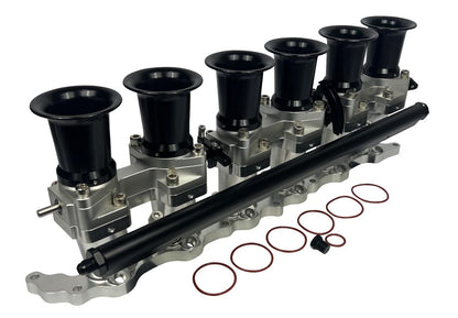 JackSpania Racing intake manifold with individual throttle bodies, fuel rail, and engine parts for 2JZGE Toyota engine.