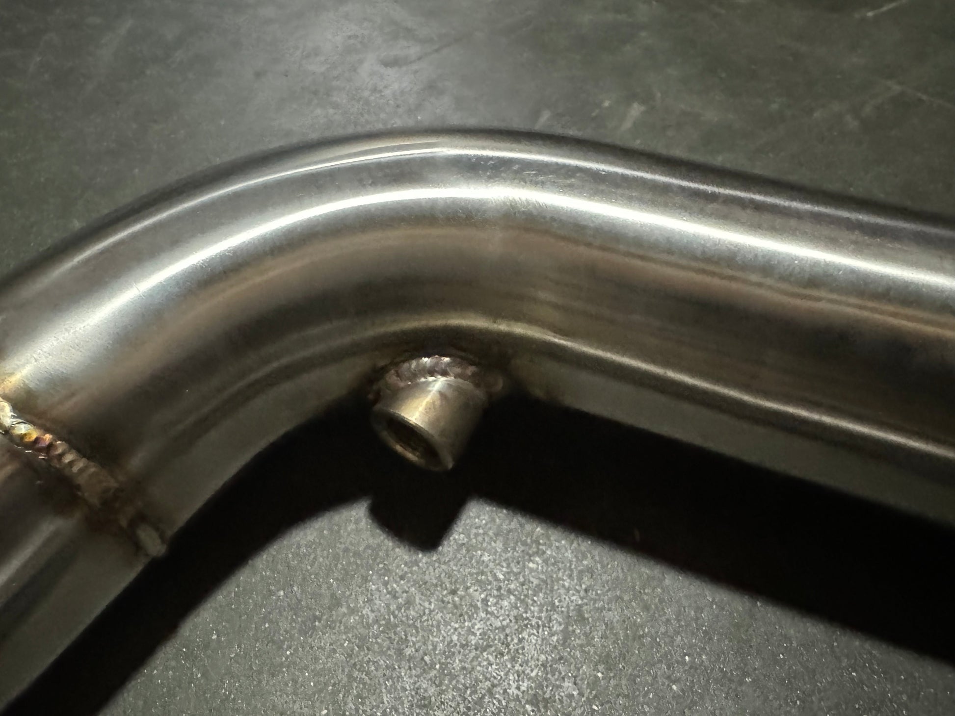 Stainless steel 3-inch downpipe for BMW S55 M3 M4 F80 F82 F87, exhaust part by JackSpania Racing, showing shiny pipe with mounting points.