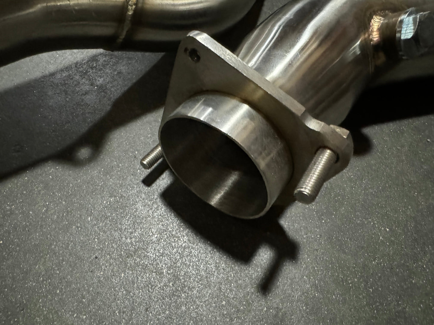 Stainless steel 3-inch downpipe for BMW S55 F80 F82 F87 M3 M4 F83 by JackSpania Racing, showing the exhaust component's polished finish.