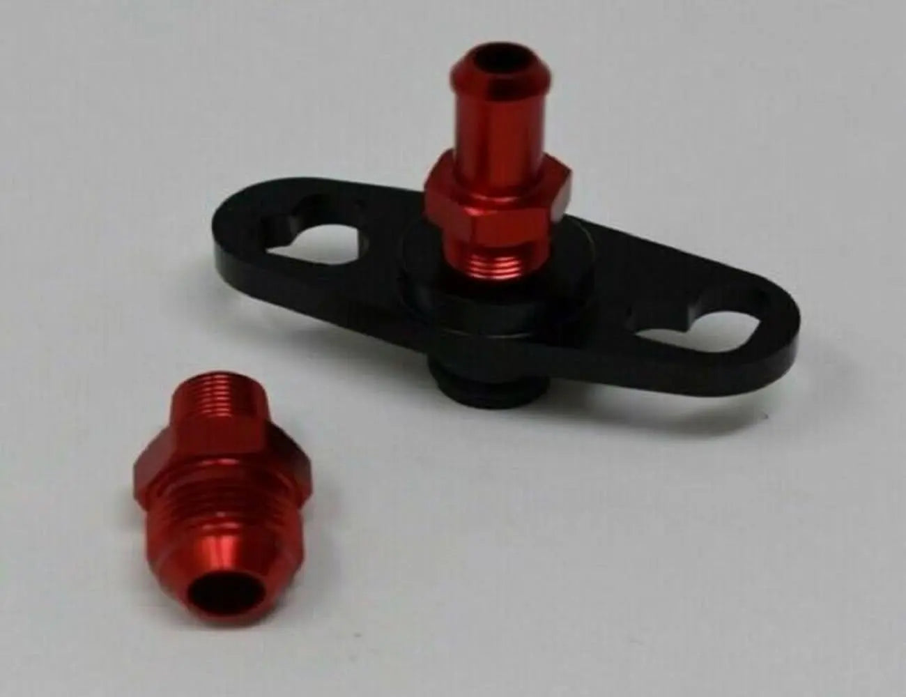 Fuel pressure regulator FPR adapter for Nissan, Subaru, Toyota engines, 1/8NPT, by Jack Spania Racing, shown installed on engine parts.